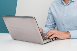 Male hands typing on laptop keyboard. Man working at home office and using lap top. Close up. of legal transcriptionist working