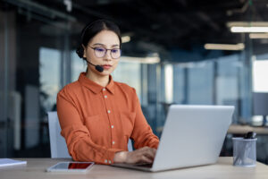 Legal transcriptionist wearing a headset while working diligently on a laptop at a modern office desk. Professional work environment.