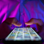 man scrolling mobile phone screen in dark room while doing social media surveillance