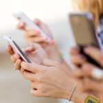 close up of three females holding phones in their hands posting on social media