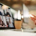 person sitting in front of a lap top for a virtual deposition. you can see 4 people on the laptop screen