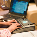 close up of stenographers hands when taking notes during trial