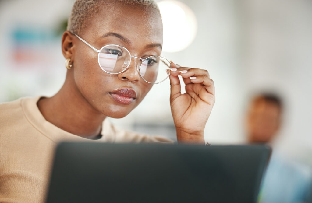 Office, computer and woman with glasses, serious or reading and proofreading a deposition summary