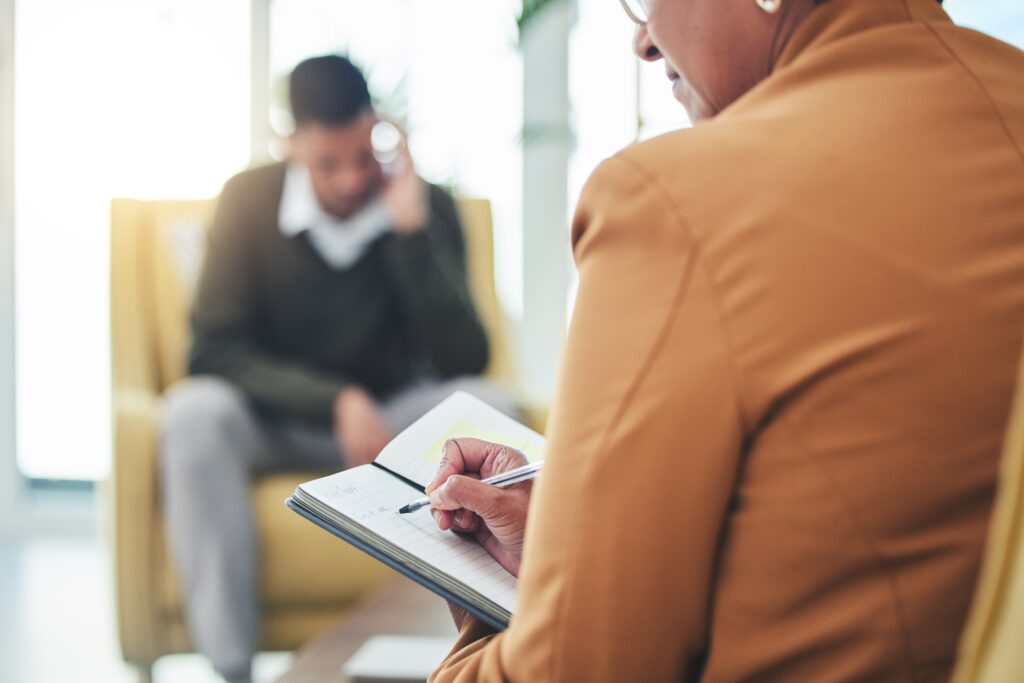 behavioral health practitioner speaking with a patient while taking notes