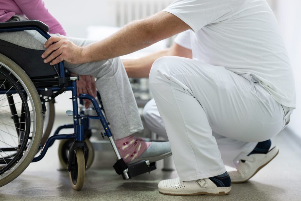 physician kneeled in front of patient who is sitting in a wheel chair